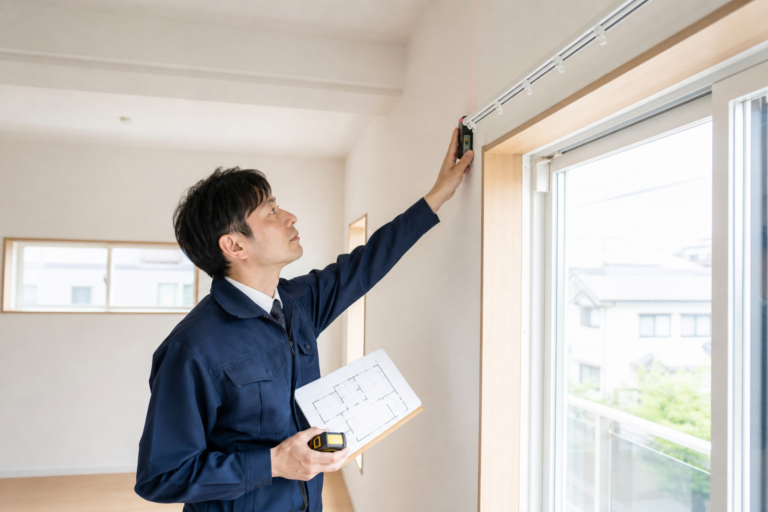 完成した新築住宅で窓を採寸する施工担当者